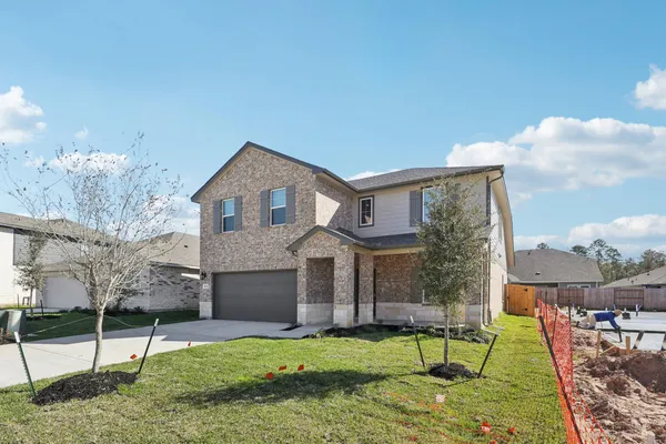 a view of a house with a yard and a large tree front of house