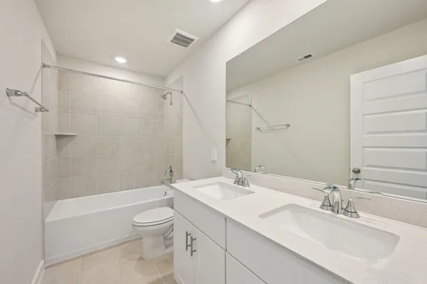 a bathroom with a bathtub shower sink vanity mirror and toilet