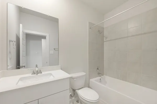 a bathroom with a bathtub shower sink vanity mirror and toilet