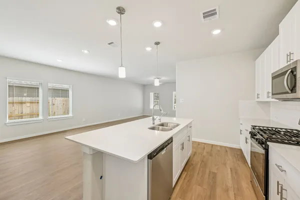 a kitchen with a sink stove and wooden floor