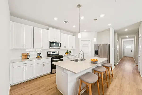 a kitchen with stainless steel appliances a stove a sink a refrigerator cabinets and a dining table
