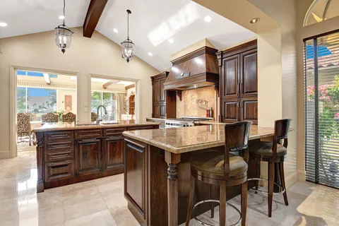 a kitchen with stainless steel appliances granite countertop a table chairs stove and refrigerator