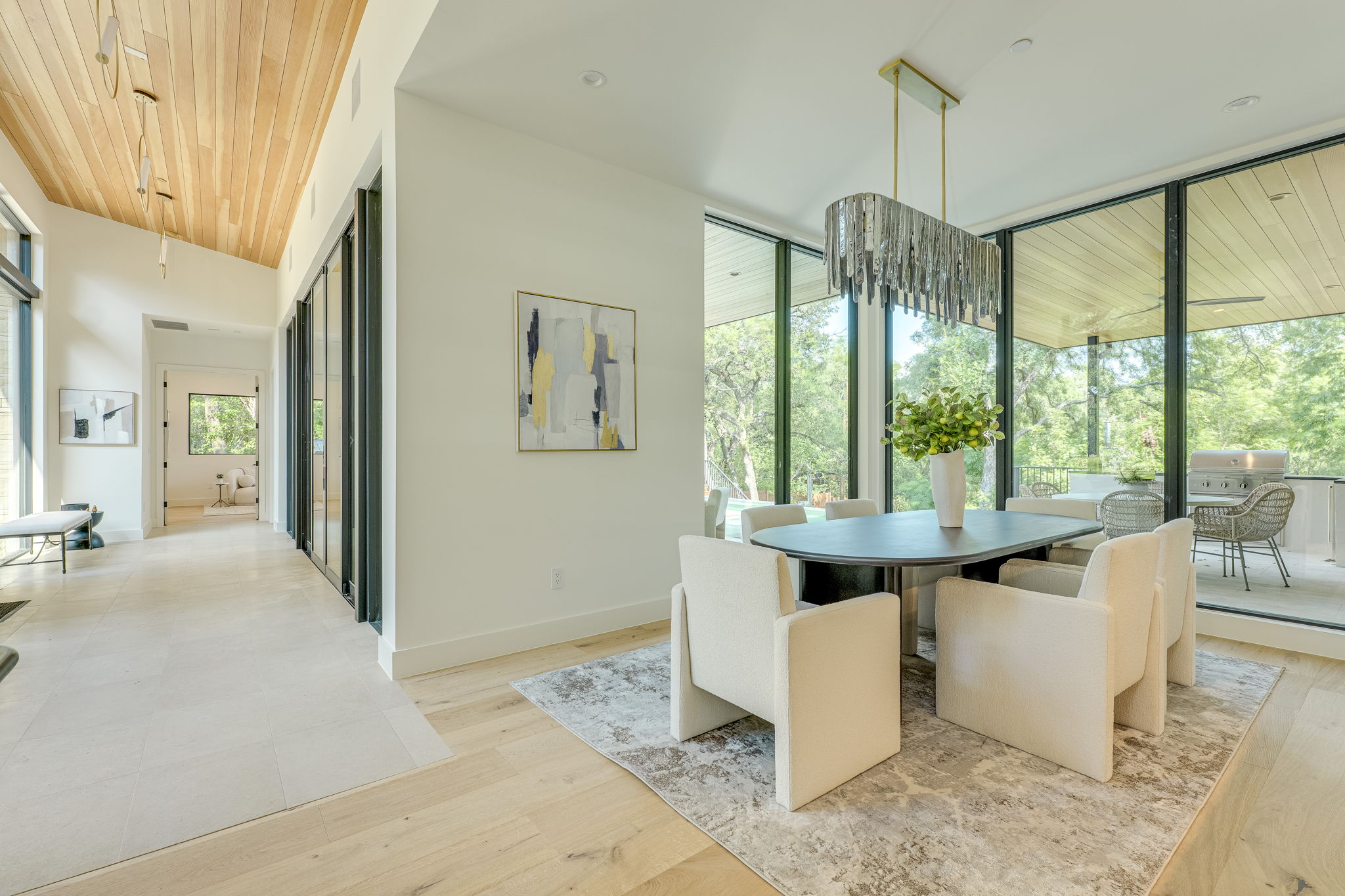 405 Honeycomb Ridge Austin, TX 78746 - Photo 6 of 15 Natural light floods this dining area, featuring a linear chandelier and expansive glass doors opening to the outdoors.