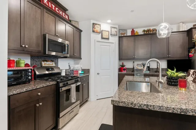 a kitchen with granite countertop a sink dishwasher stove and cabinets with wooden floor