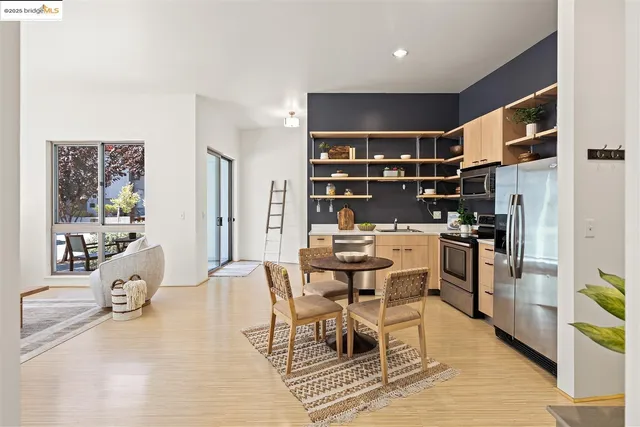 a dining room with stainless steel appliances kitchen island granite countertop a dining table chairs and a refrigerator