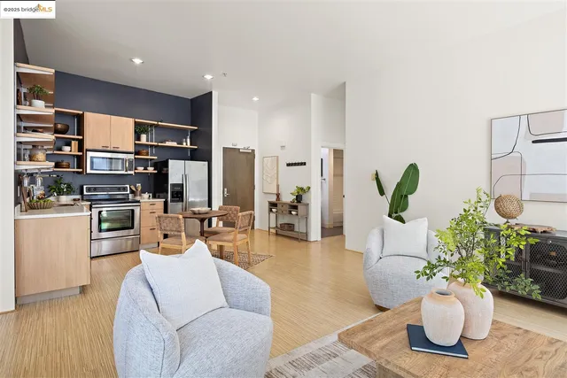 a living room with furniture potted plant and kitchen view
