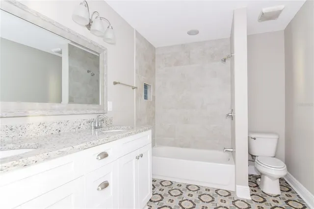 a bathroom with a granite countertop sink a toilet and shower