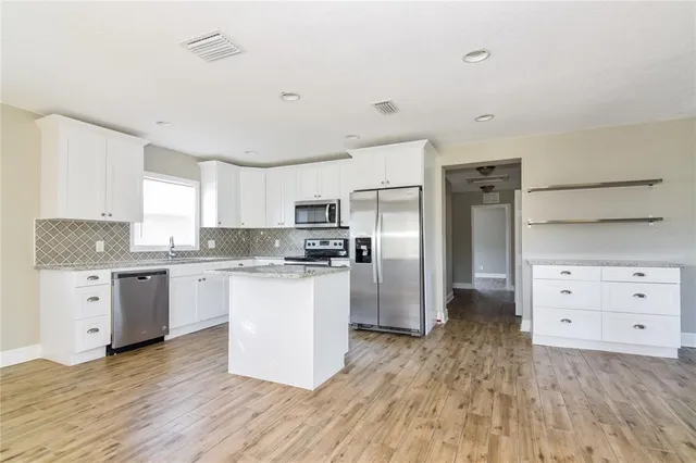 a kitchen with granite countertop white cabinets and stainless steel appliances