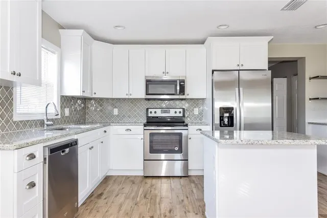 a kitchen with kitchen island a counter top space a sink stainless steel appliances and cabinets