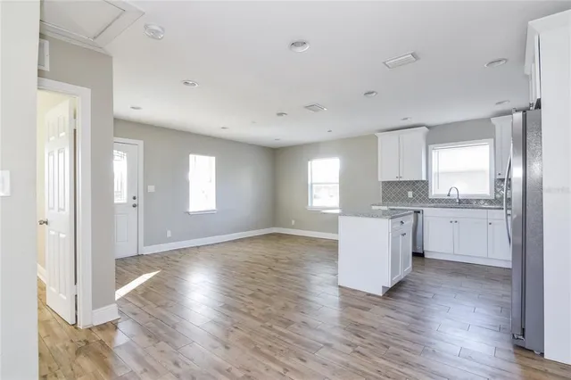 a view of an empty room with window and wooden floor