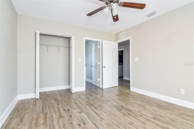 an empty room with wooden floor and ceiling fan