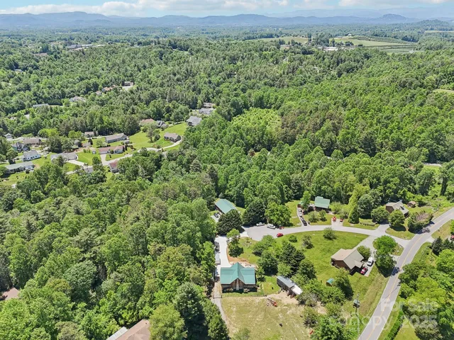 an aerial view of residential house with outdoor space and trees all around