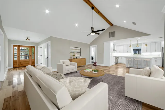 a living room with furniture kitchen view and a large window