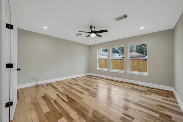 a view of empty room with wooden floor and fan