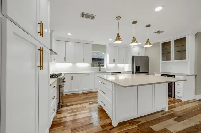 a kitchen with stainless steel appliances granite countertop a sink a stove a refrigerator and island with wooden floor