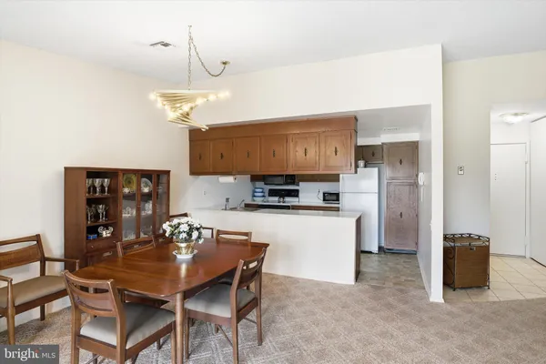 a kitchen with stainless steel appliances kitchen island granite countertop a dining table chairs and a refrigerator