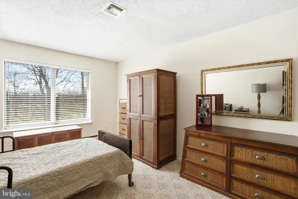 a bedroom with a bed and a large mirror on a dresser
