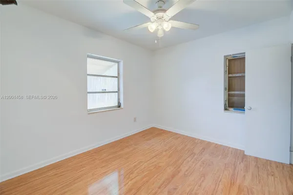 an empty room with a window and a fan