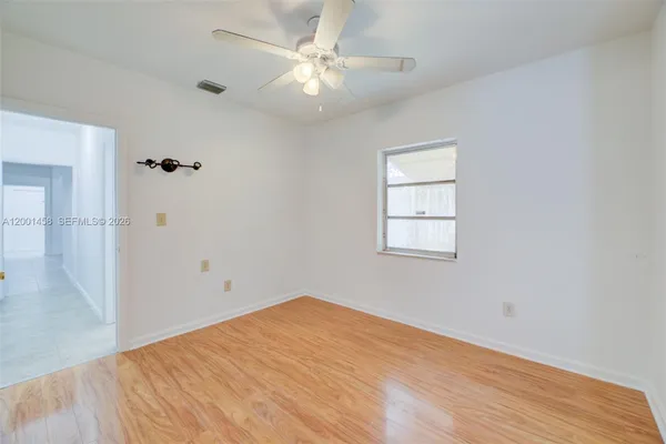 an empty room with wooden floor fan and windows