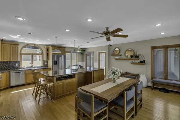 a kitchen with granite countertop a stove a sink a dining table and chairs with wooden floor