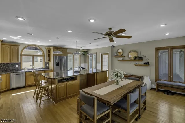 a kitchen with granite countertop a stove a sink a dining table and chairs with wooden floor