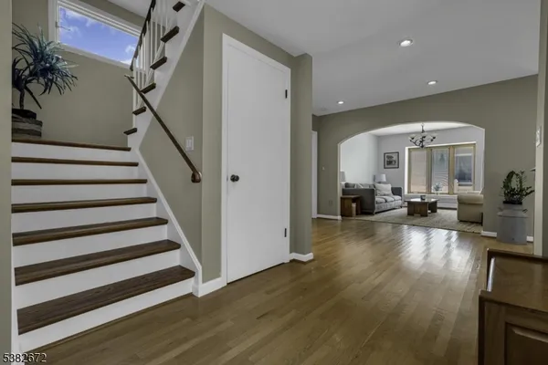 a view of a livingroom with furniture staircase wooden floor and windows