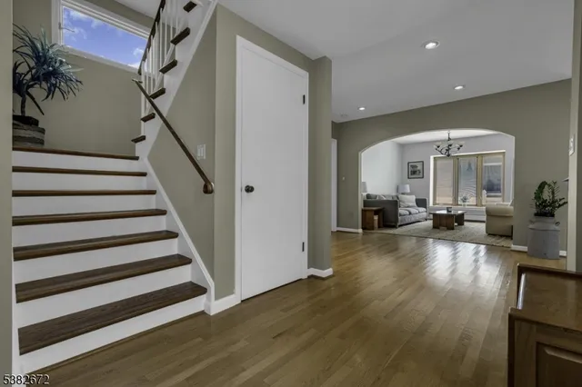 a view of a livingroom with furniture staircase wooden floor and windows