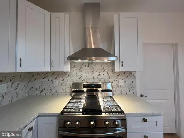a kitchen with a stove and white cabinets