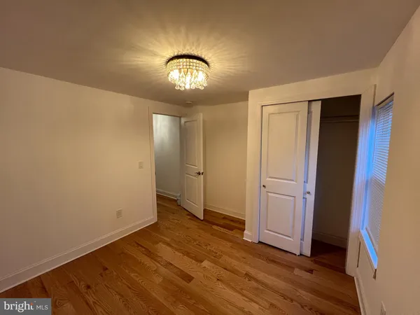 an empty room with wooden floor and hallway
