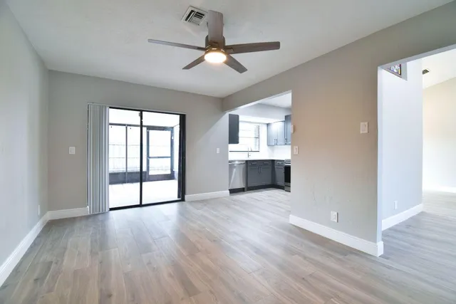 a view of an empty room with a window and wooden floor