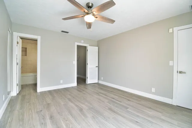 an empty room with wooden floor and ceiling fan
