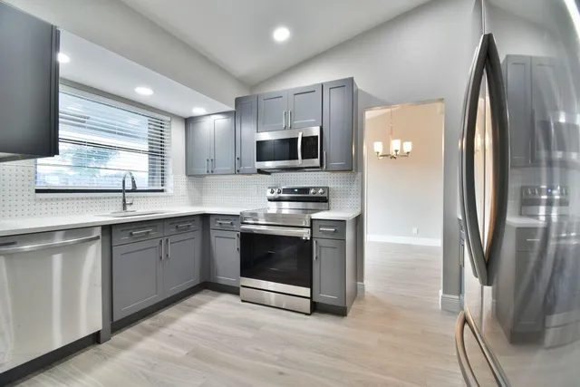 a kitchen with stainless steel appliances granite countertop a refrigerator a sink a stove a microwave and island