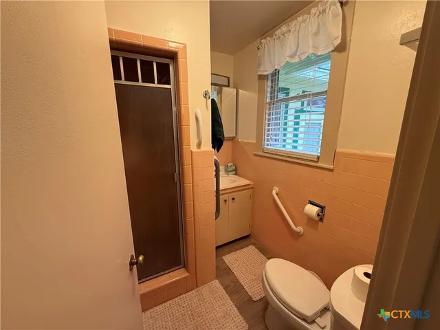 a bathroom with a sink a toilet a window and shower