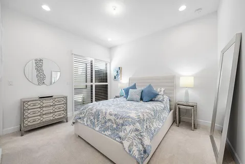 a bedroom with a bed a dresser and next to a window