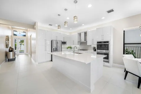 a large white kitchen with lots of counter space a refrigerator cabinets and a counter top space