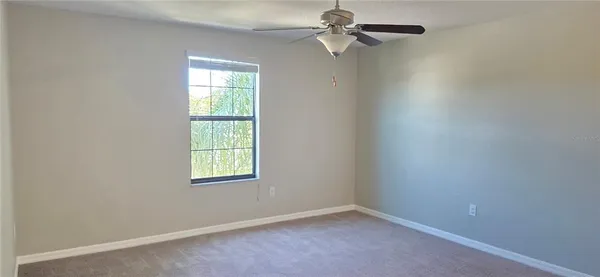an empty room with windows and fan