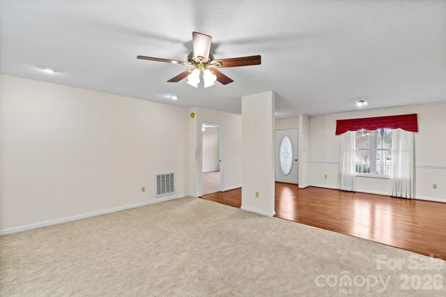 a view of an empty room with window and wooden floor