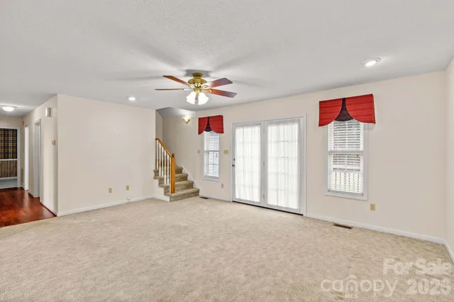 an empty room with windows and chandelier fan