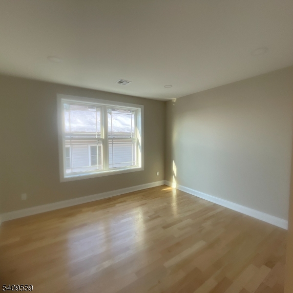 1297 Avy Street Hillside, NJ 07205 - Photo 12 of 15 an empty room with wooden floor and windows