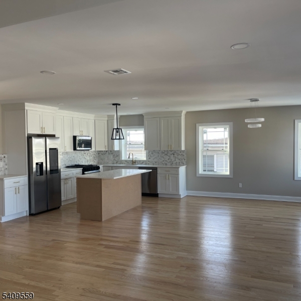 1297 Avy Street Hillside, NJ 07205 - Photo 2 of 15 a large kitchen with stainless steel appliances granite countertop a refrigerator a sink dishwasher a oven with white cabinets and wooden floor