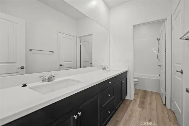 a spacious bathroom with a double vanity sink a mirror and a toilet