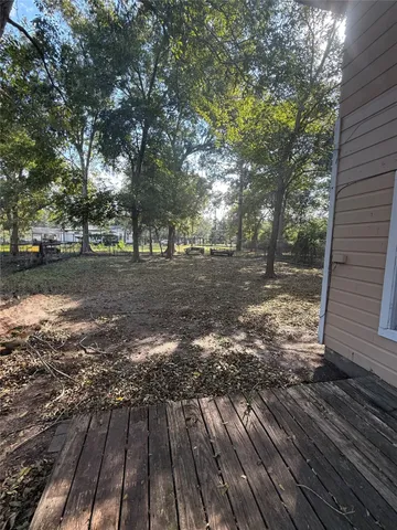 a view of a yard with wooden deck and trees