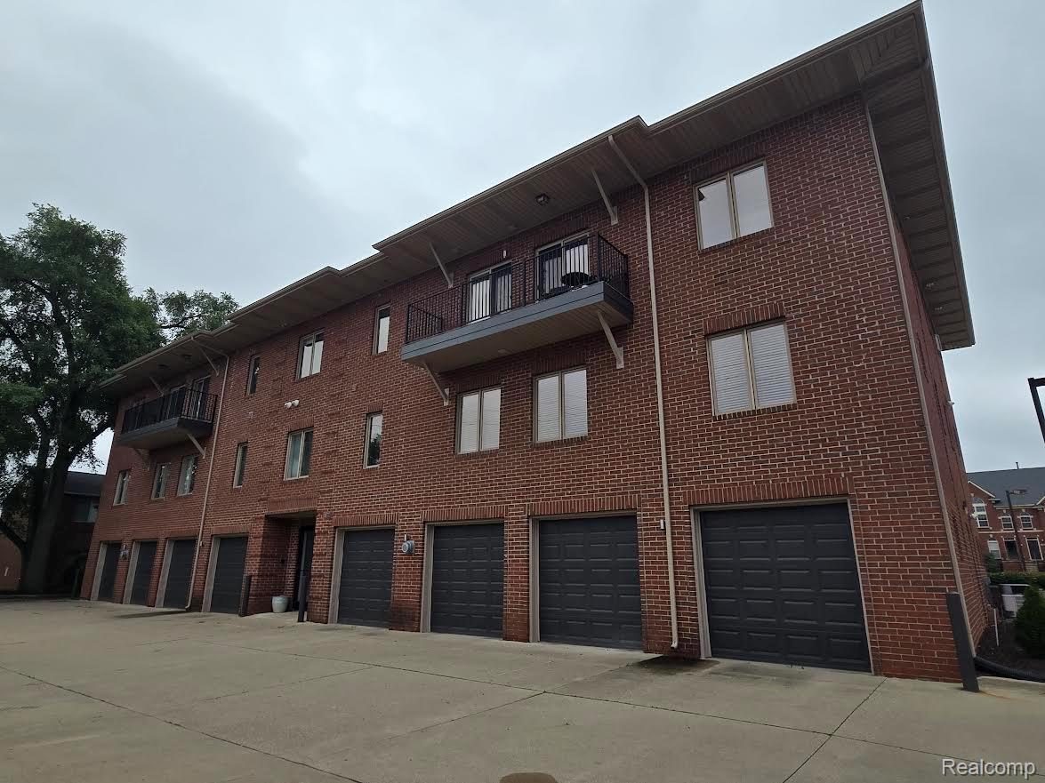 2727 East Maple Road Birmingham, MI 48009 - Photo 29 of 29 Brick exterior facade with multiple windows, individual garage doors, and private balconies