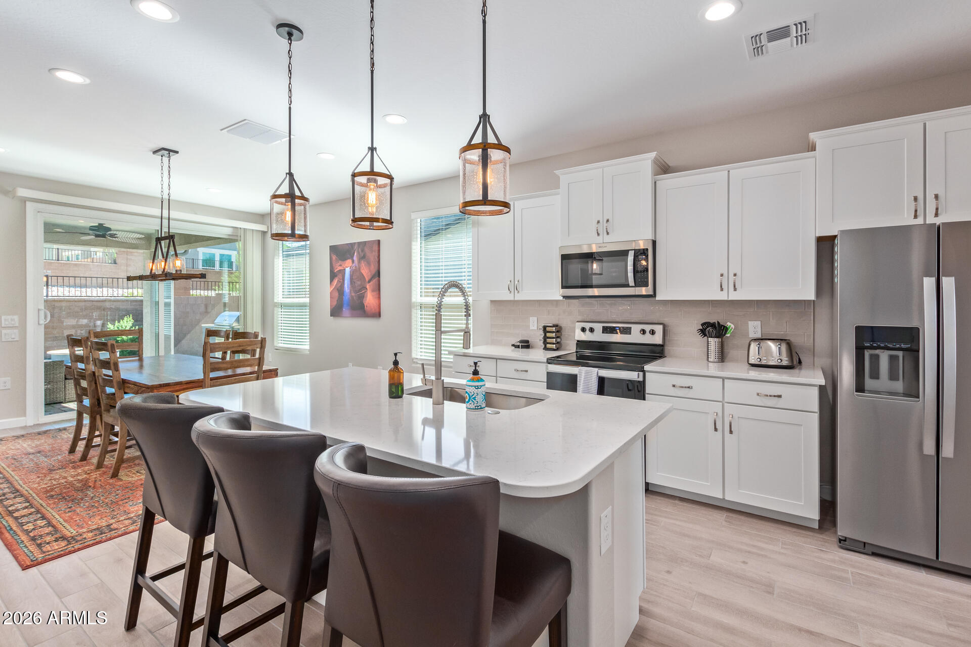 a kitchen with stainless steel appliances granite countertop a dining table chairs refrigerator and microwave