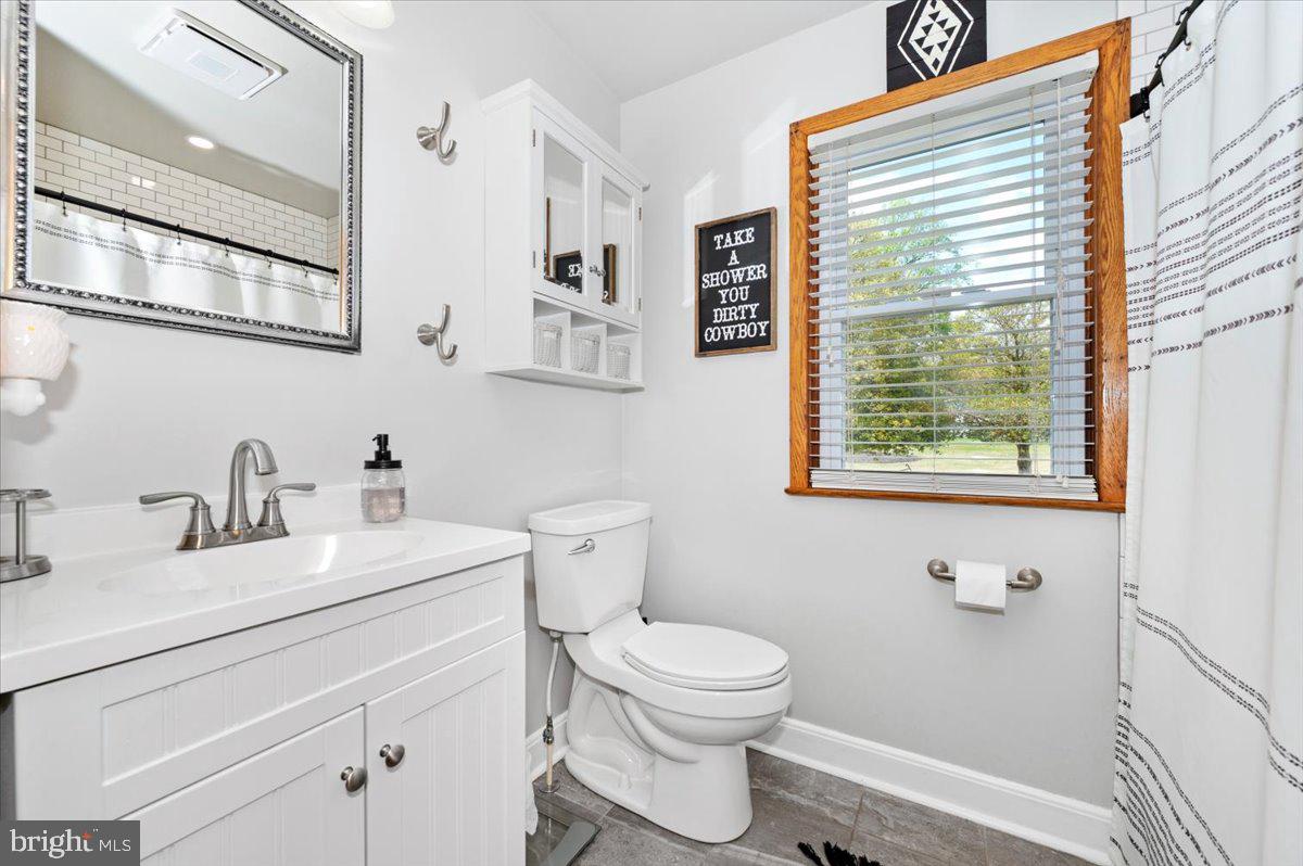7117 Blue Mountain Road Thurmont, MD 21788 - Photo 29 of 80 a bathroom with a granite countertop toilet a sink a mirror and a window