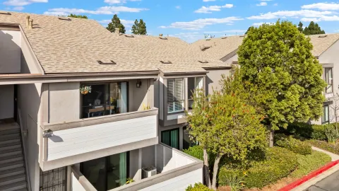 a view of a white house with large windows and a small yard