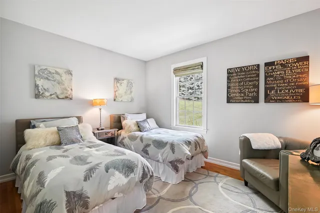 a bedroom with two beds and a large mirror next to a window