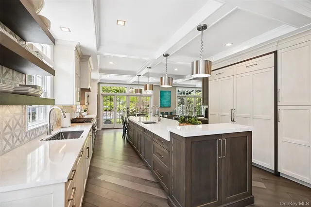 a large white kitchen with a large window a sink and stainless steel appliances
