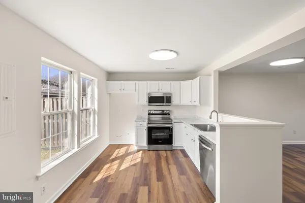 a kitchen with stainless steel appliances wooden floor and a window