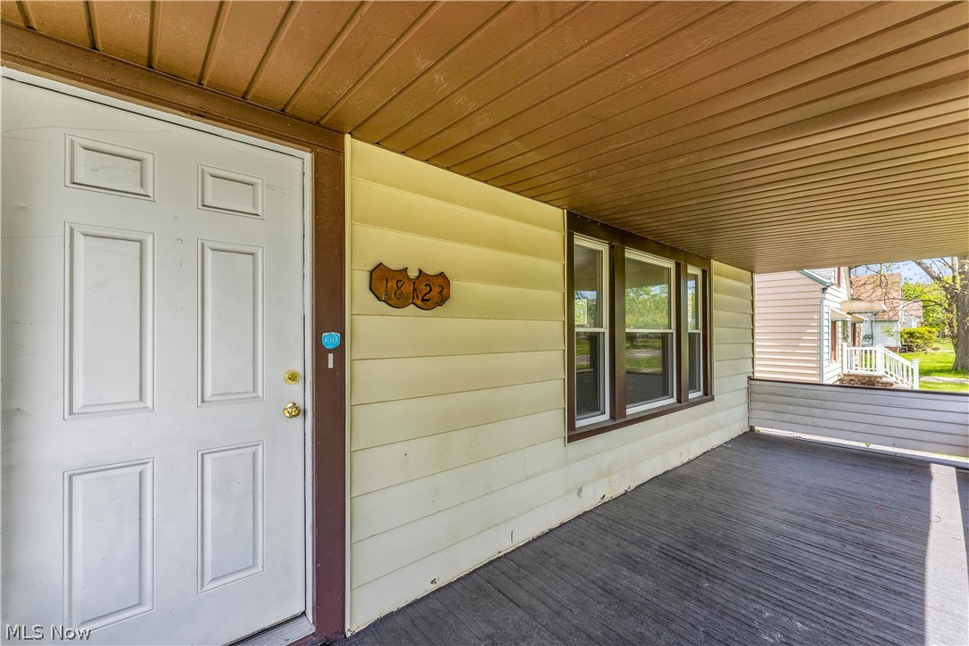 18123 McCracken Road Maple Heights, OH 44137 - Photo 3 of 27 Covered front porch featuring a paneled entry door, wood-finish porch flooring, and a multi-pane window